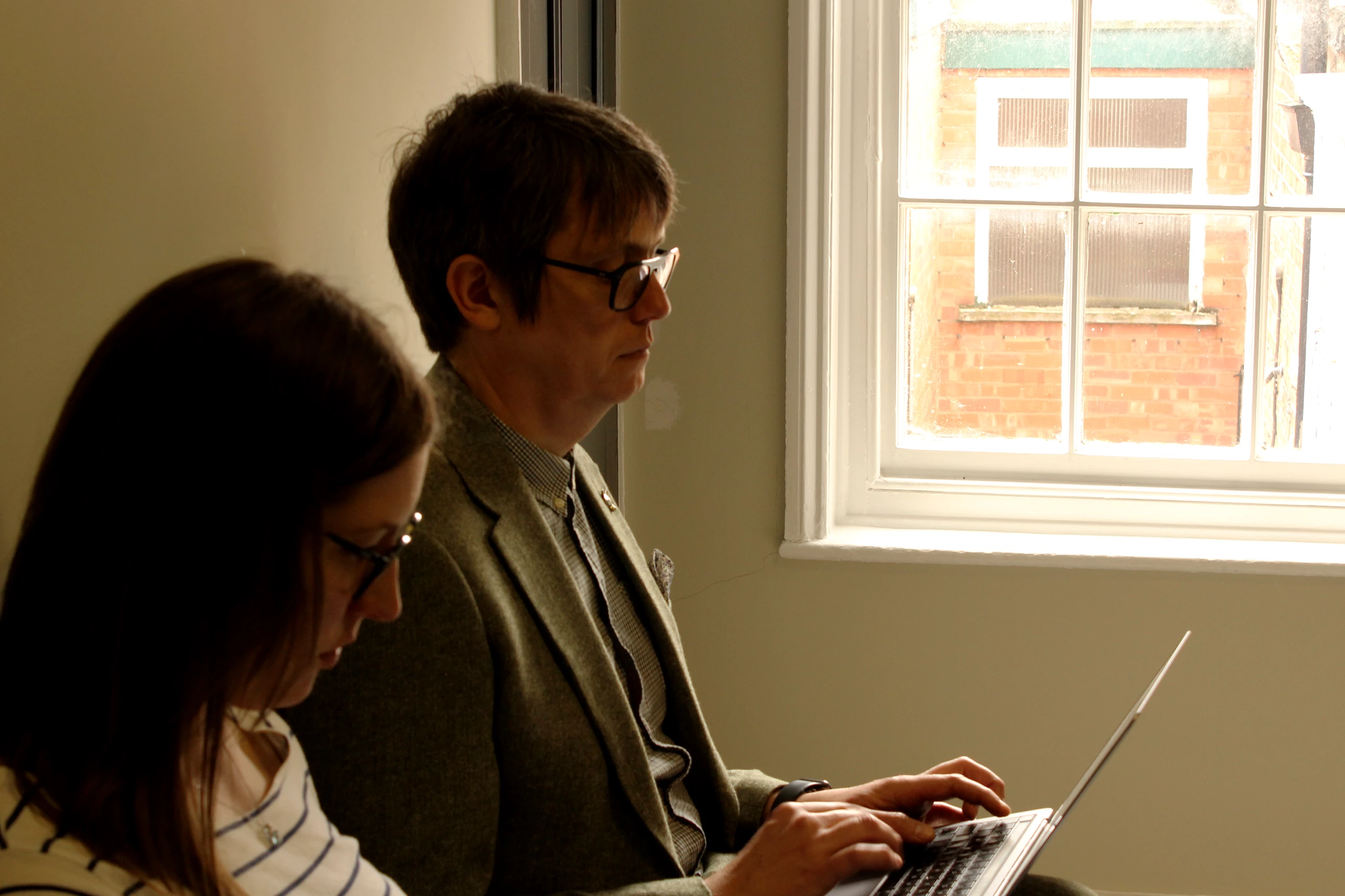 Project manager Katy and Digital Director and co-founder Mat sit side-by-side, both looking at Macbook screens