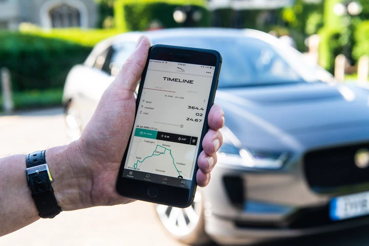 Hand holding Jaguar I-Pace app in front of Jaguar car