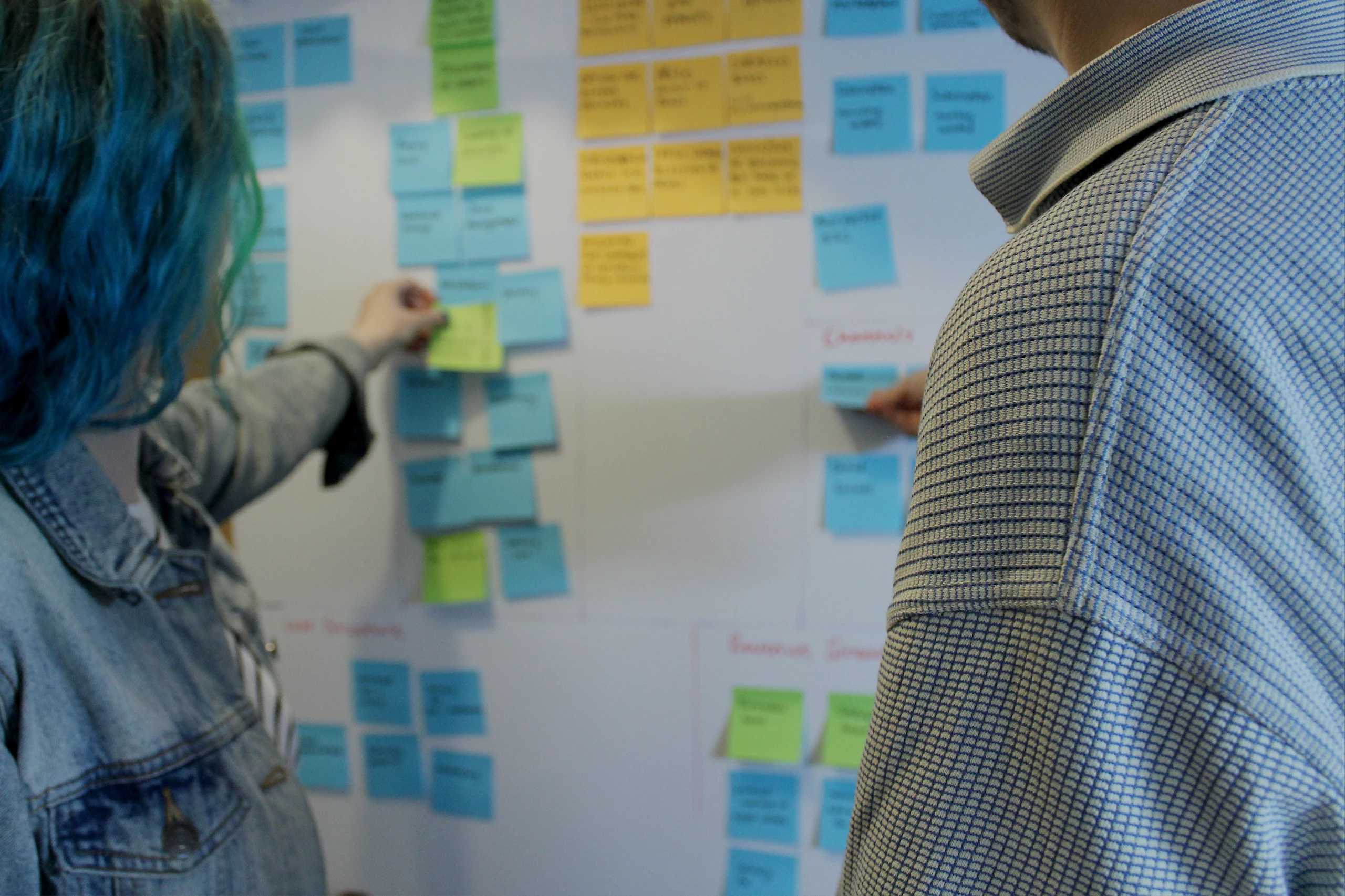 Designer Abi and Digital Engagement Manager Dom moving notes on the whiteboard in the Bulb Studios lounge