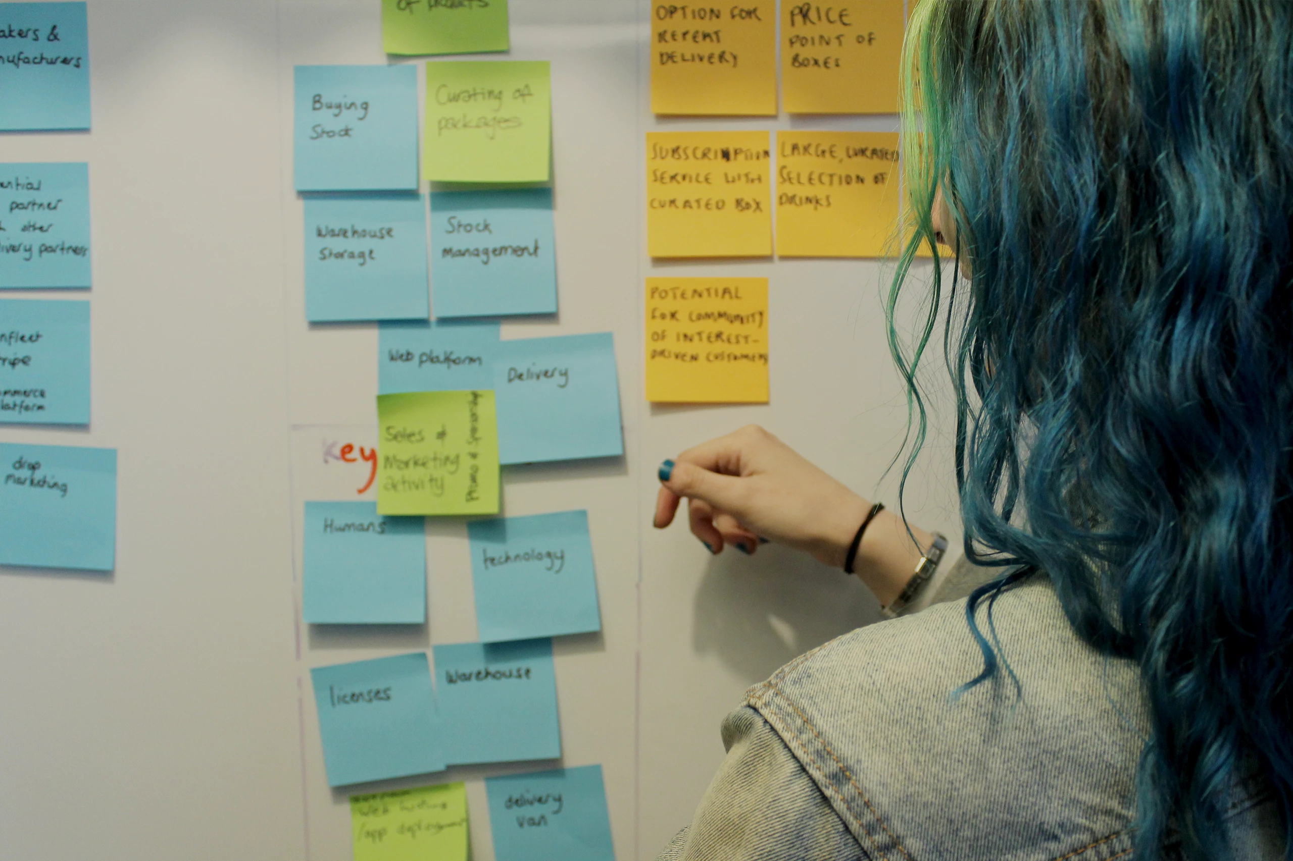 Designer Abi moving post-it notes on the whiteboard in the Bulb Studios lounge