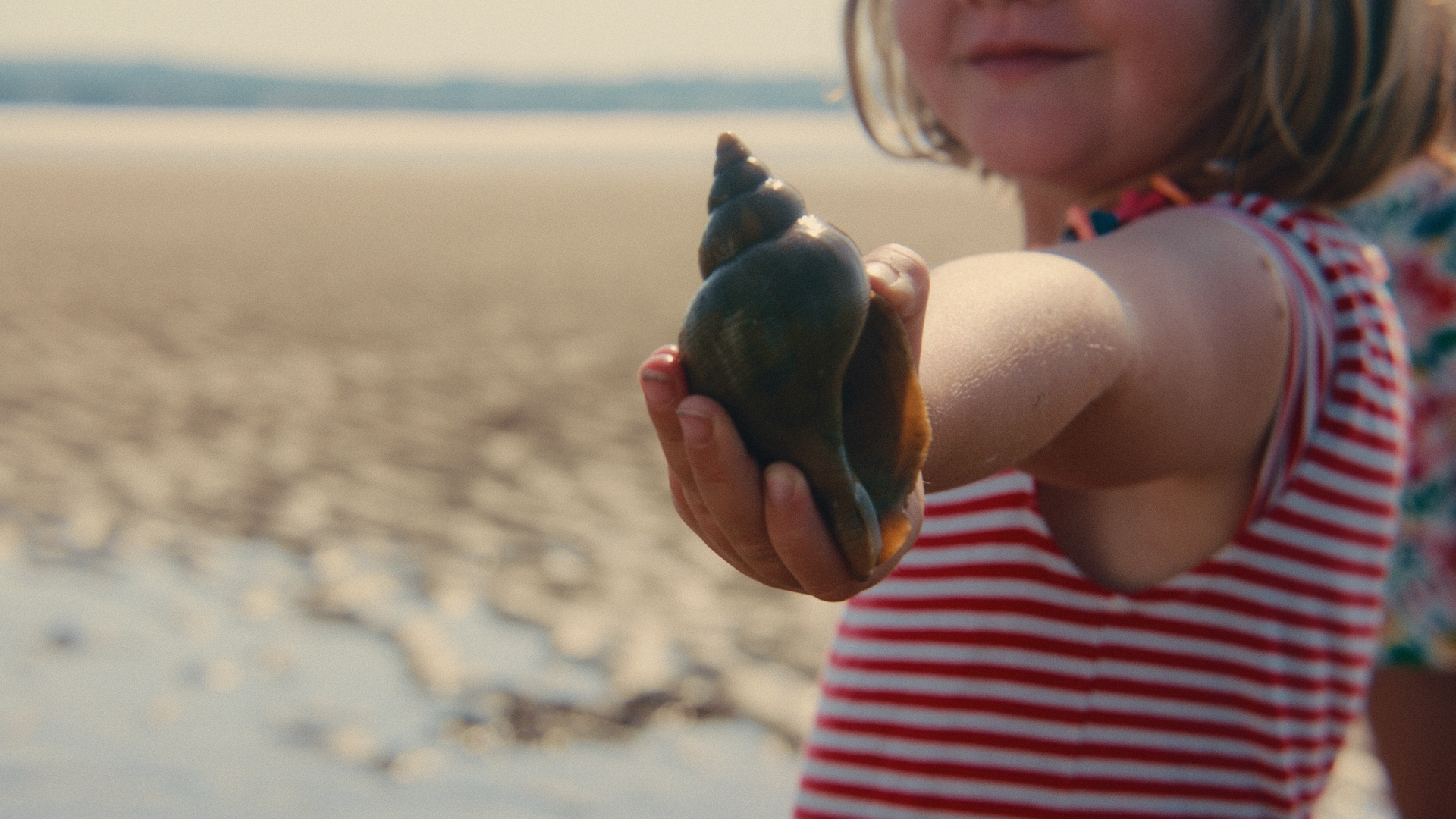 girl holding shell on beach in scotland