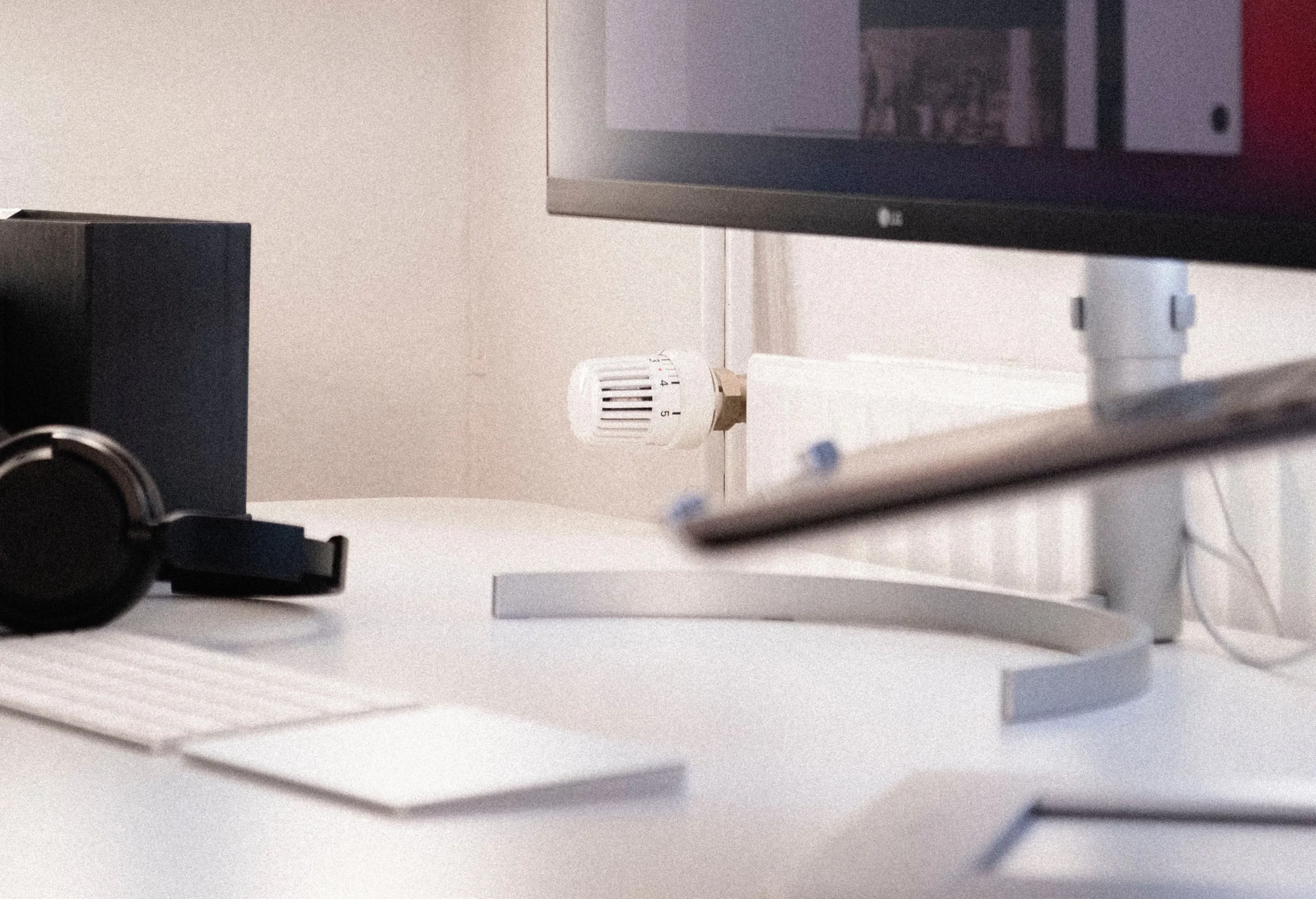 a minimalist desk set-up with monitor, keyboard, trackpad and headphones